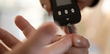 Billede af bloddråbe på finger og blodsukkermåling.